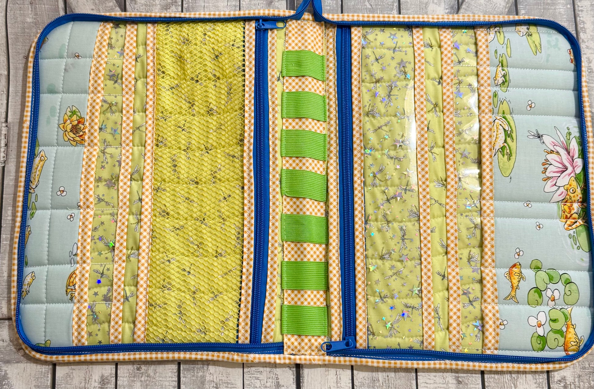 Inside of sewing tool organizer with mesh pockets, vinyl pockets, and elastic loops in green and gingham prints