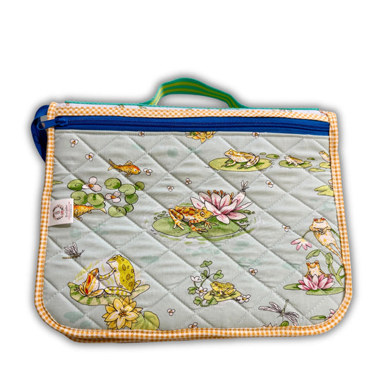 Quilted sewing tool organizer with frogs and lily pads, logo tag on left, orange gingham trim and bright zipper