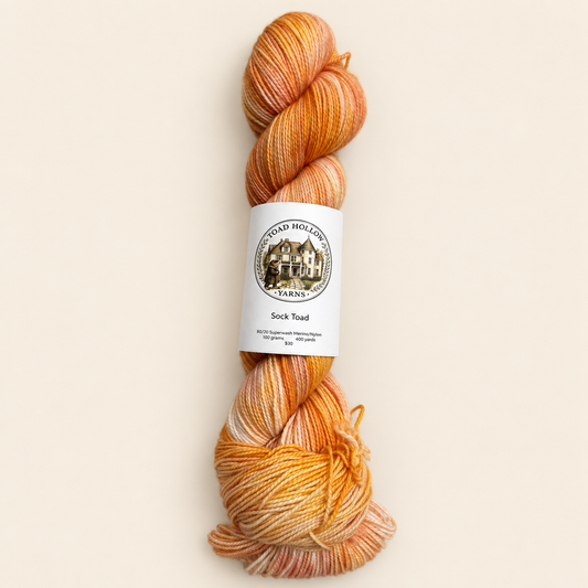 product photo of one skein of Umbrella Drinks a bright orange variegated hand dyed yarn from toad hollow.  Main color is orange with a peachy pink undertone